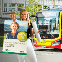 Linda steht mit Plakat vor einem TüBus