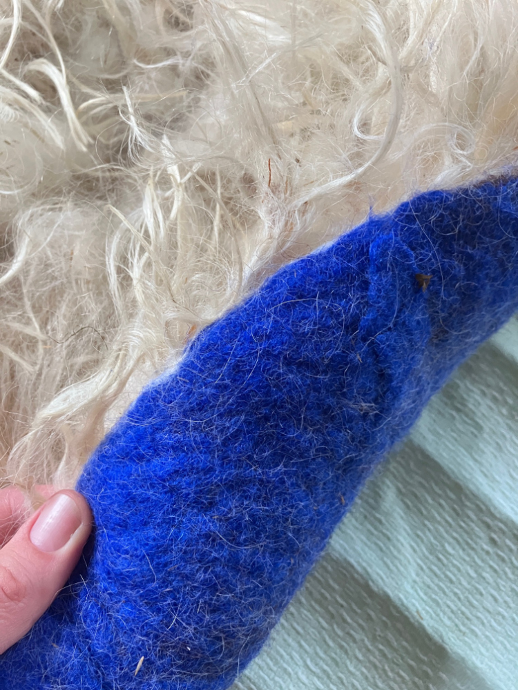 Schafwolle wird in Lauge gefilzt und die Unterseite des Kissens blau gefärbt